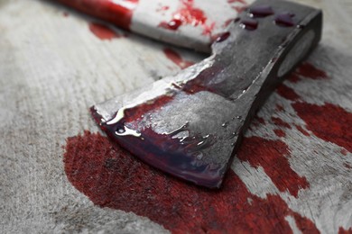 Photo of Axe with blood on wooden surface, closeup