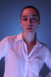 Photo of Portrait of beautiful young woman on blue background with neon lights