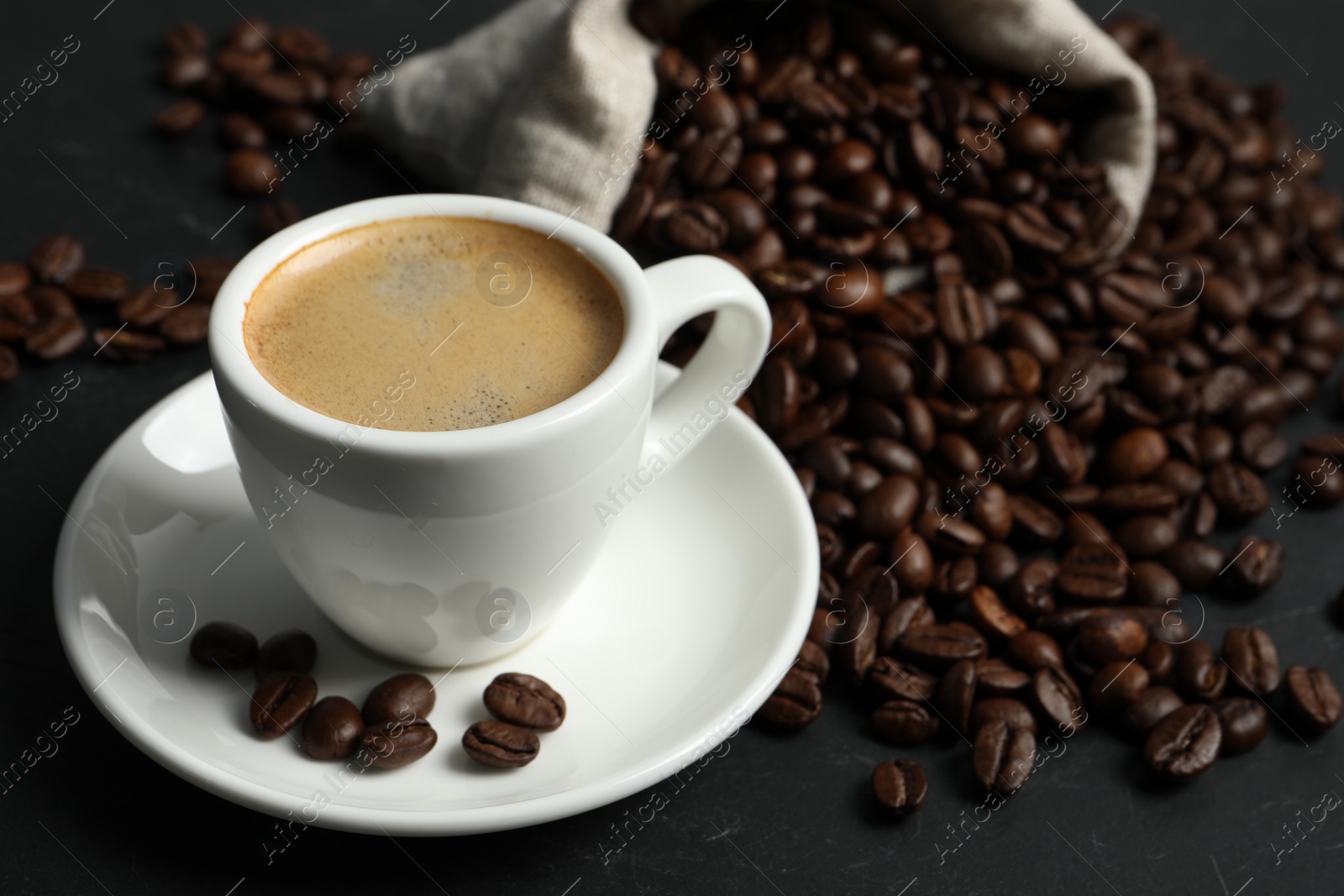 Photo of Cup of aromatic coffee and beans on grey table. Space for text