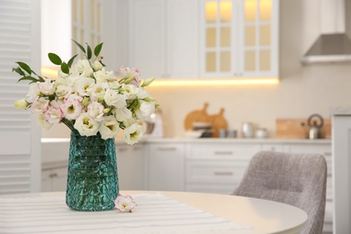 Photo of Bouquet of beautiful flowers on table in kitchen, space for text. Interior design
