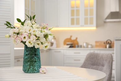 Bouquet of beautiful flowers on table in kitchen, space for text. Interior design