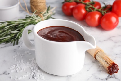 Photo of Composition with jug of barbecue sauce on marble table