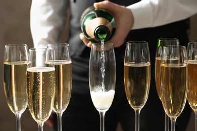 Waiter pouring champagne into glass, closeup view