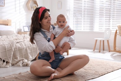 Photo of Happy young mother with her cute baby on floor in bedroom