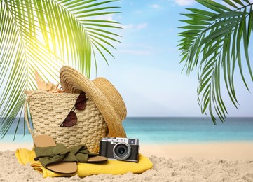 Image of Bag with accessories and vintage camera on sunny ocean beach, space for text. Summer vacation