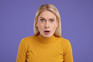 Portrait of surprised woman on violet background