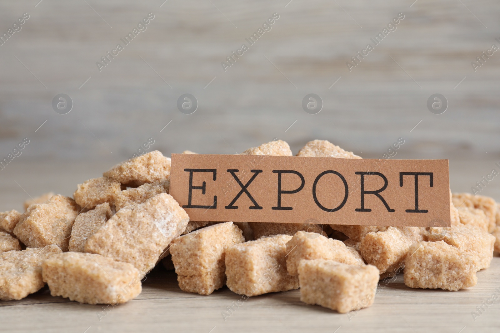 Photo of Card with word EXPORT and brown sugar on white wooden table, closeup