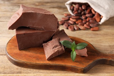 Photo of Pieces of tasty milk chocolate and mint on wooden table, closeup