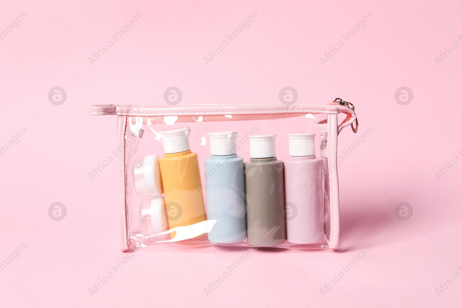 Photo of Cosmetic travel kit in plastic bag on pink background