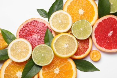 Photo of Fresh juicy citrus fruits with green leaves on white background, flat lay