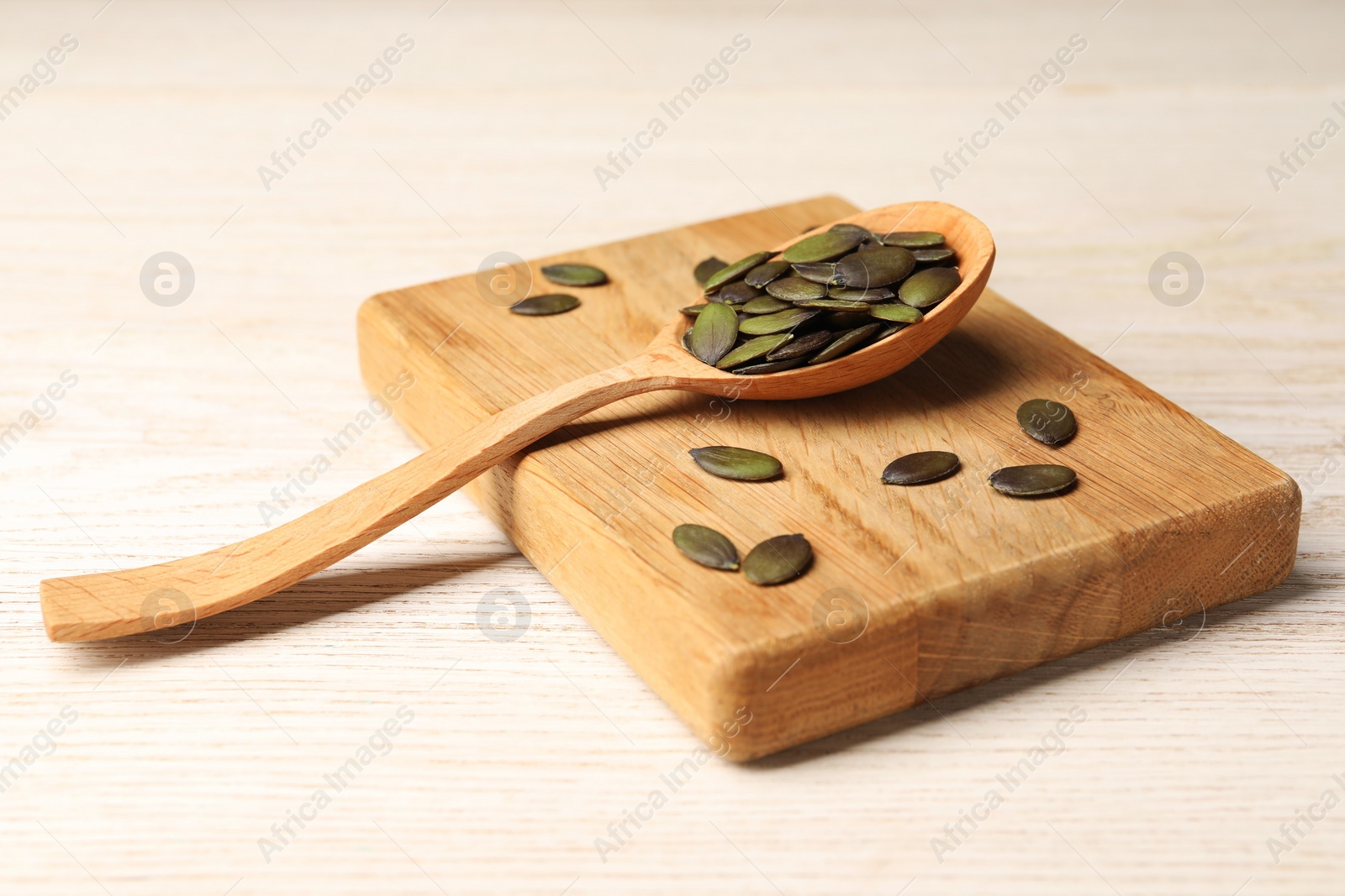 Photo of Spoon with pumpkin seeds on wooden table, closeup