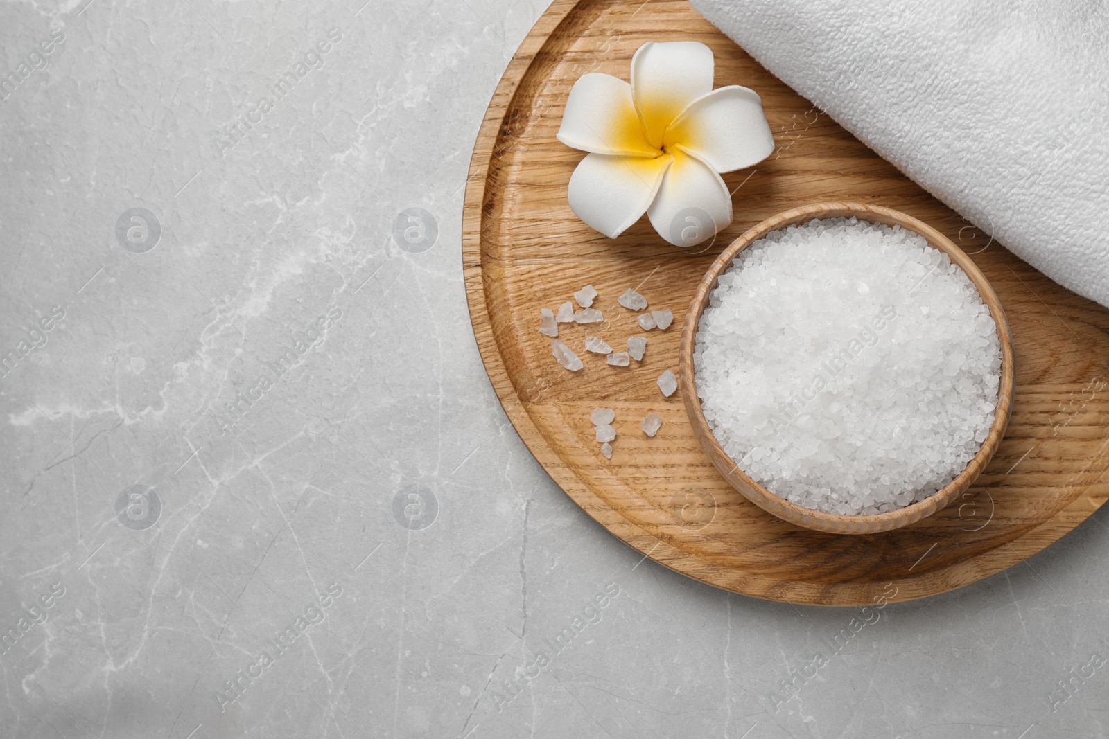 Photo of Sea salt, towel and flower on grey marble table, top view with space for text. Spa treatment