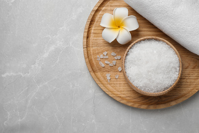 Sea salt, towel and flower on grey marble table, top view with space for text. Spa treatment