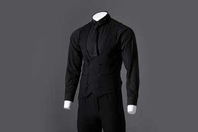 Male mannequin dressed in stylish black suit on grey background