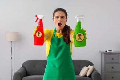 Photo of Woman showing bottles of toxic household chemical with warning signs