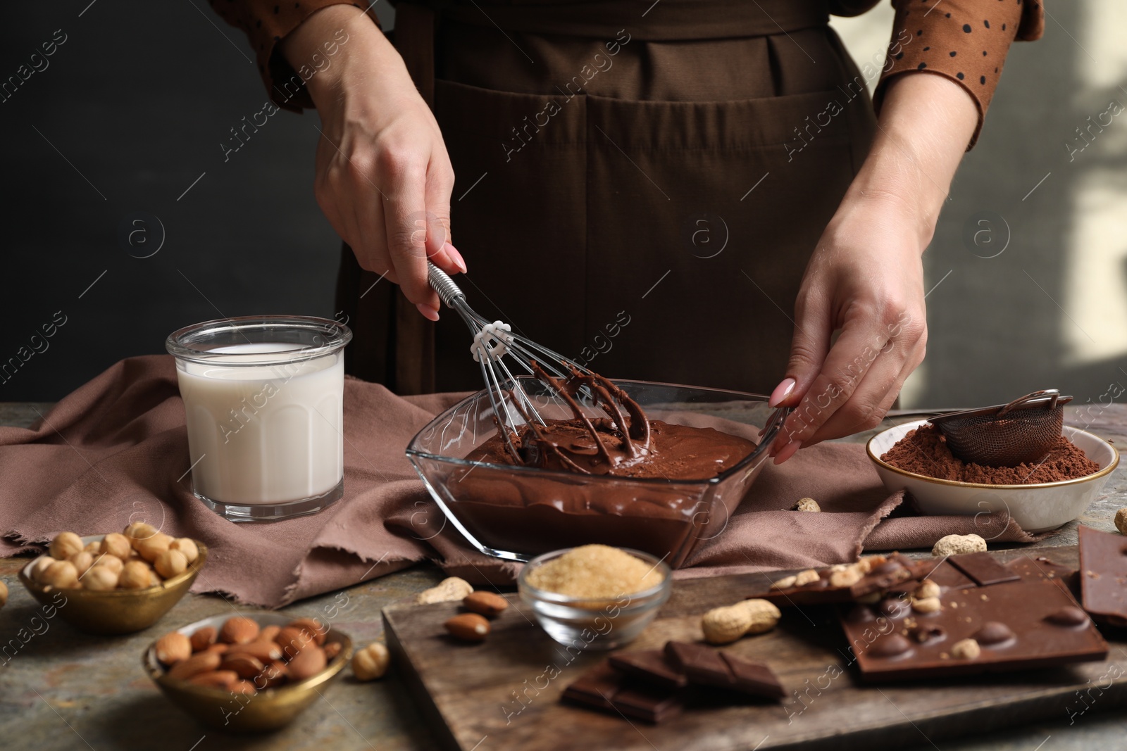 Photo of Woman mixing delicious chocolate cream with whisk at table, closeup