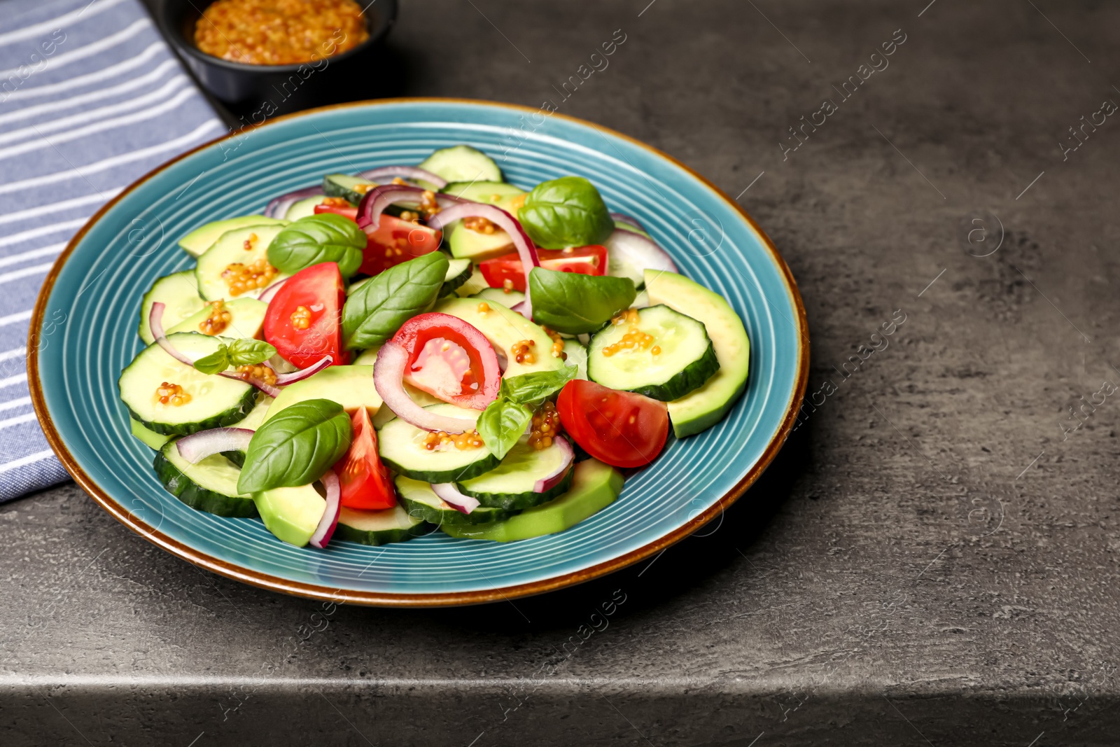 Photo of Tasty salad with cucumbers served on grey table