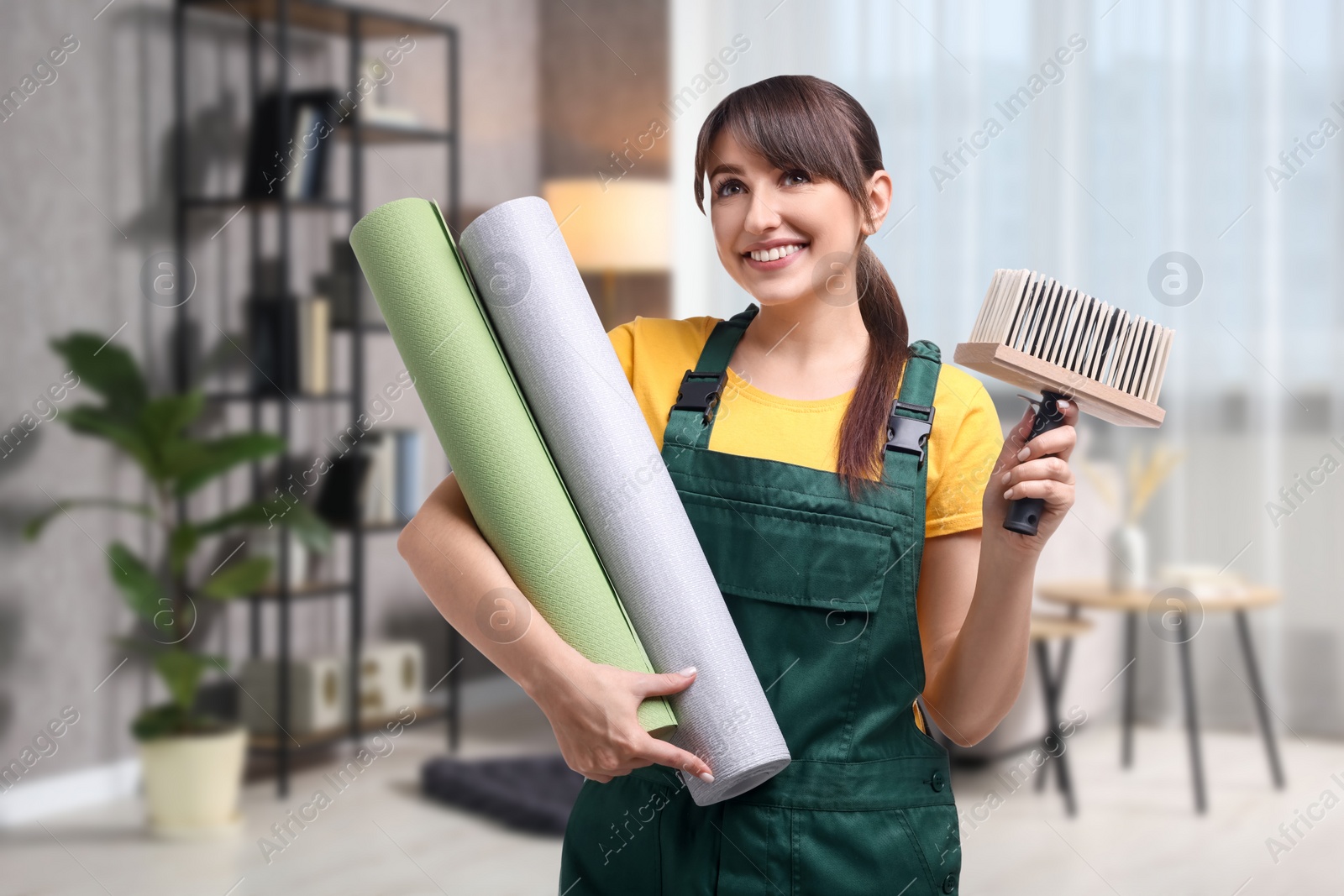 Image of Woman with wallpaper rolls and brush in room