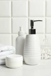 Different bath accessories and personal care products on white table near tiled wall