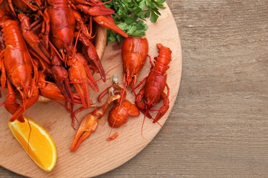 Delicious red boiled crayfish and orange on wooden table, top view. Space for text