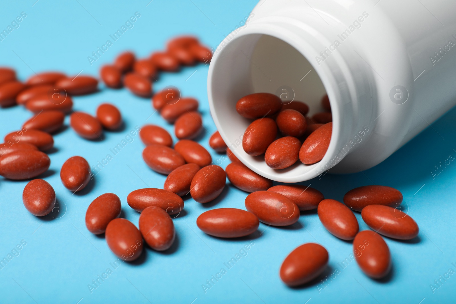 Photo of Bottle with pills on light blue background, closeup