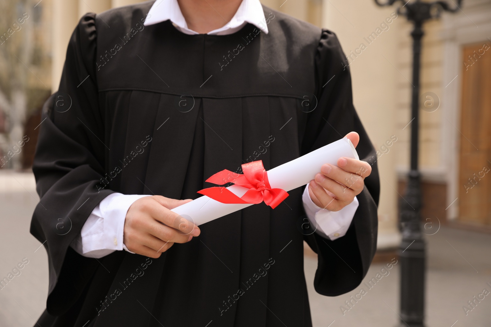 Photo of Student with diploma after graduation ceremony outdoors, closeup