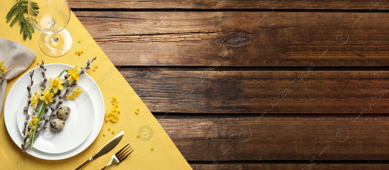 Image of Festive Easter table setting with quail eggs and floral decor on wooden background, flat lay. Space for text