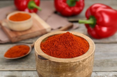 Photo of Bowl with aromatic paprika powder on wooden table, closeup