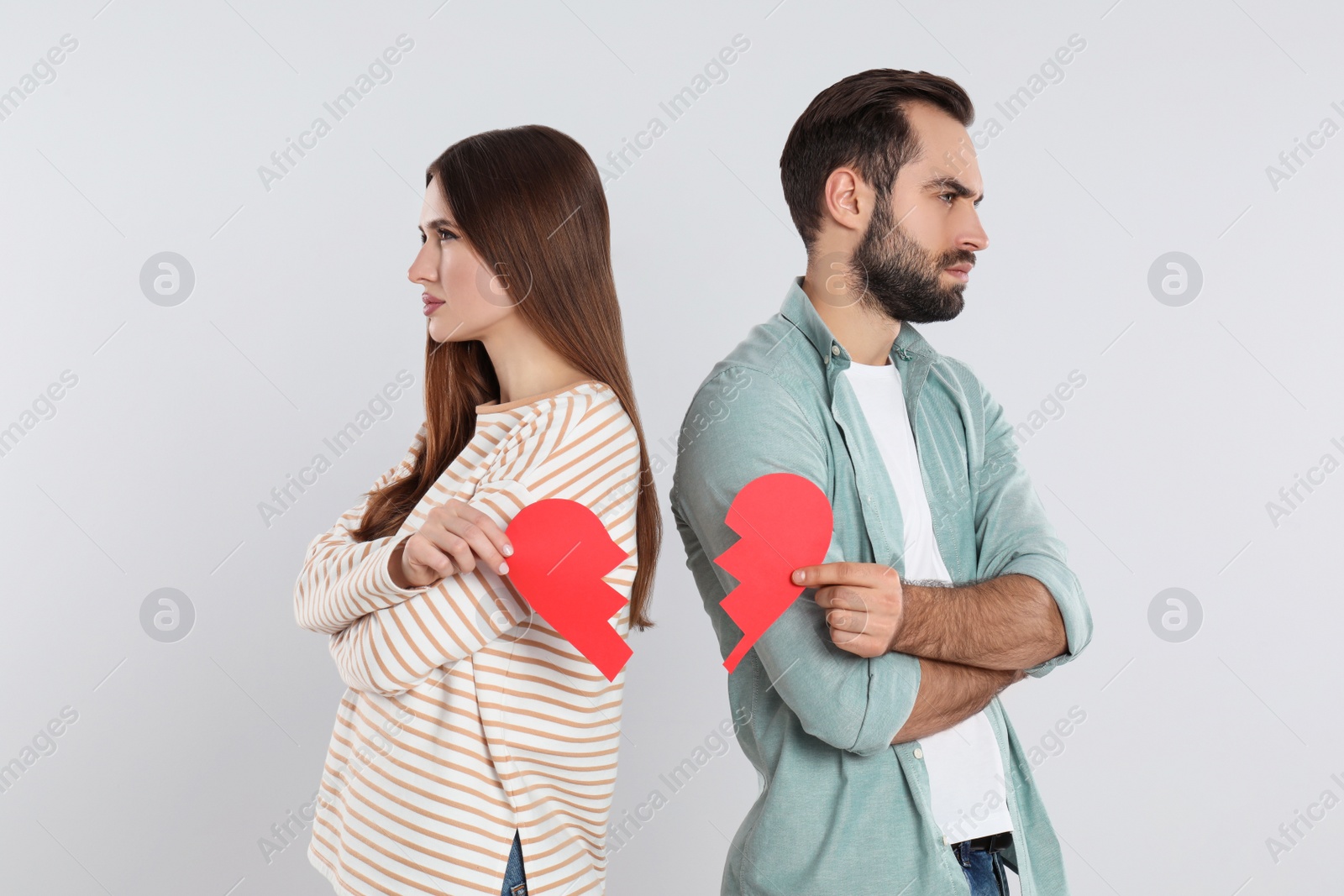 Photo of Couple with torn paper heart on light background. Relationship problems