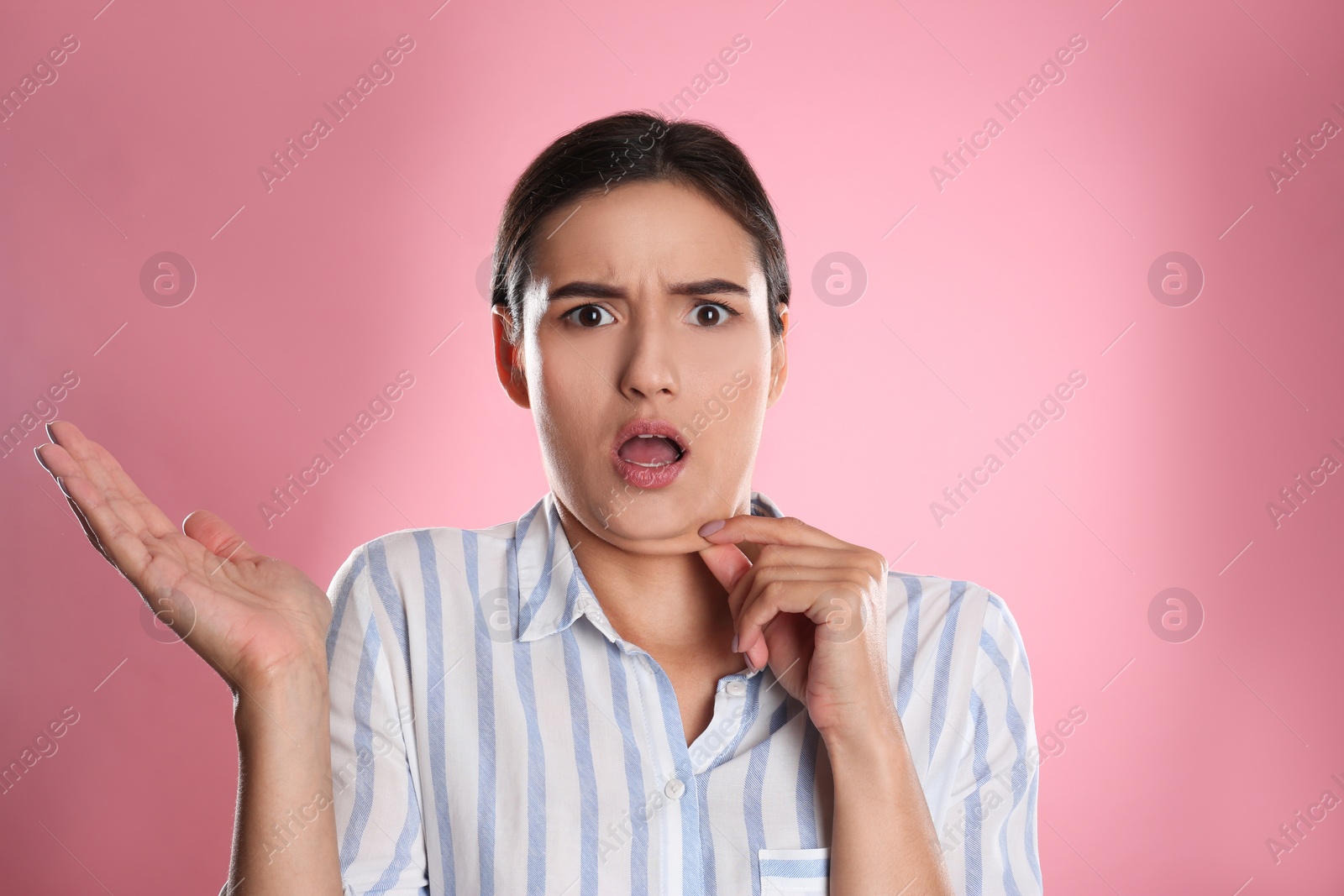 Photo of Emotional young woman with double chin on pink background