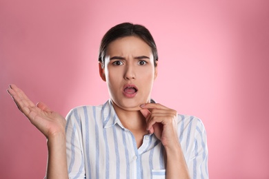 Emotional young woman with double chin on pink background