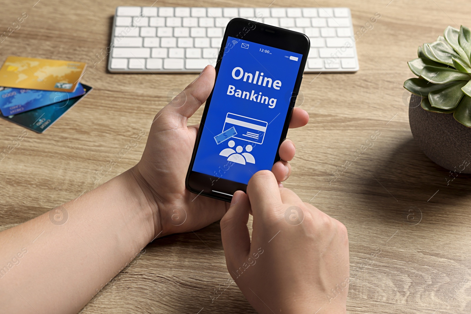 Photo of Man using online banking app on smartphone at wooden office table, closeup