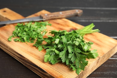 Photo of Wooden board with fresh green parsley and knife on table, closeup