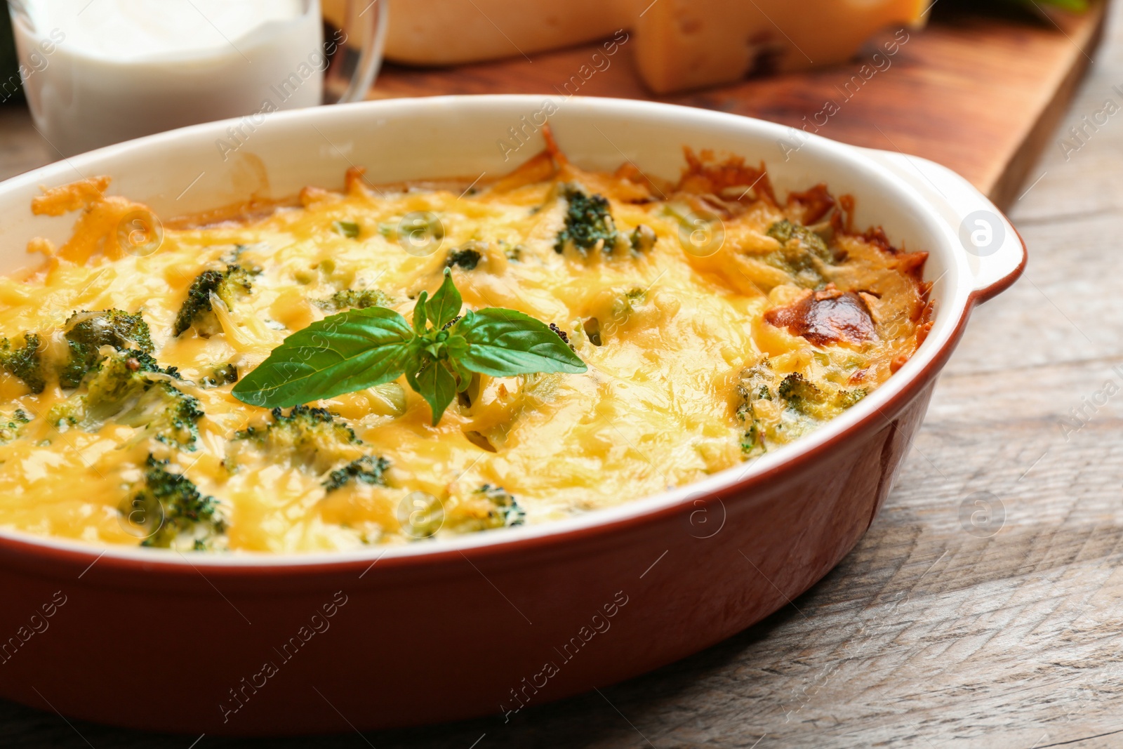 Photo of Tasty broccoli casserole in baking dish on wooden table, closeup