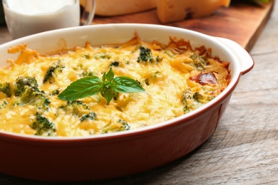 Photo of Tasty broccoli casserole in baking dish on wooden table, closeup