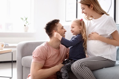 Young pregnant woman with her family at home