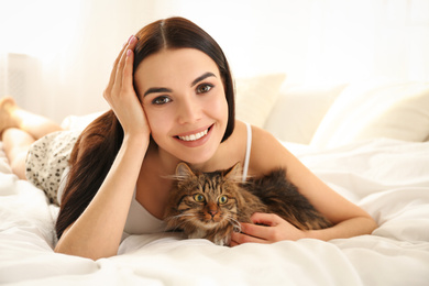 Photo of Beautiful young woman with her cute cat on bed. Fluffy pet