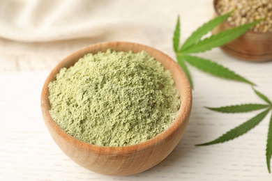 Photo of Bowl of hemp protein powder on white wooden table, closeup