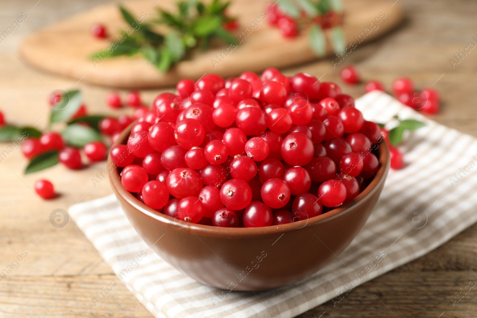 Photo of Bowl with tasty ripe cranberries on table, closeup