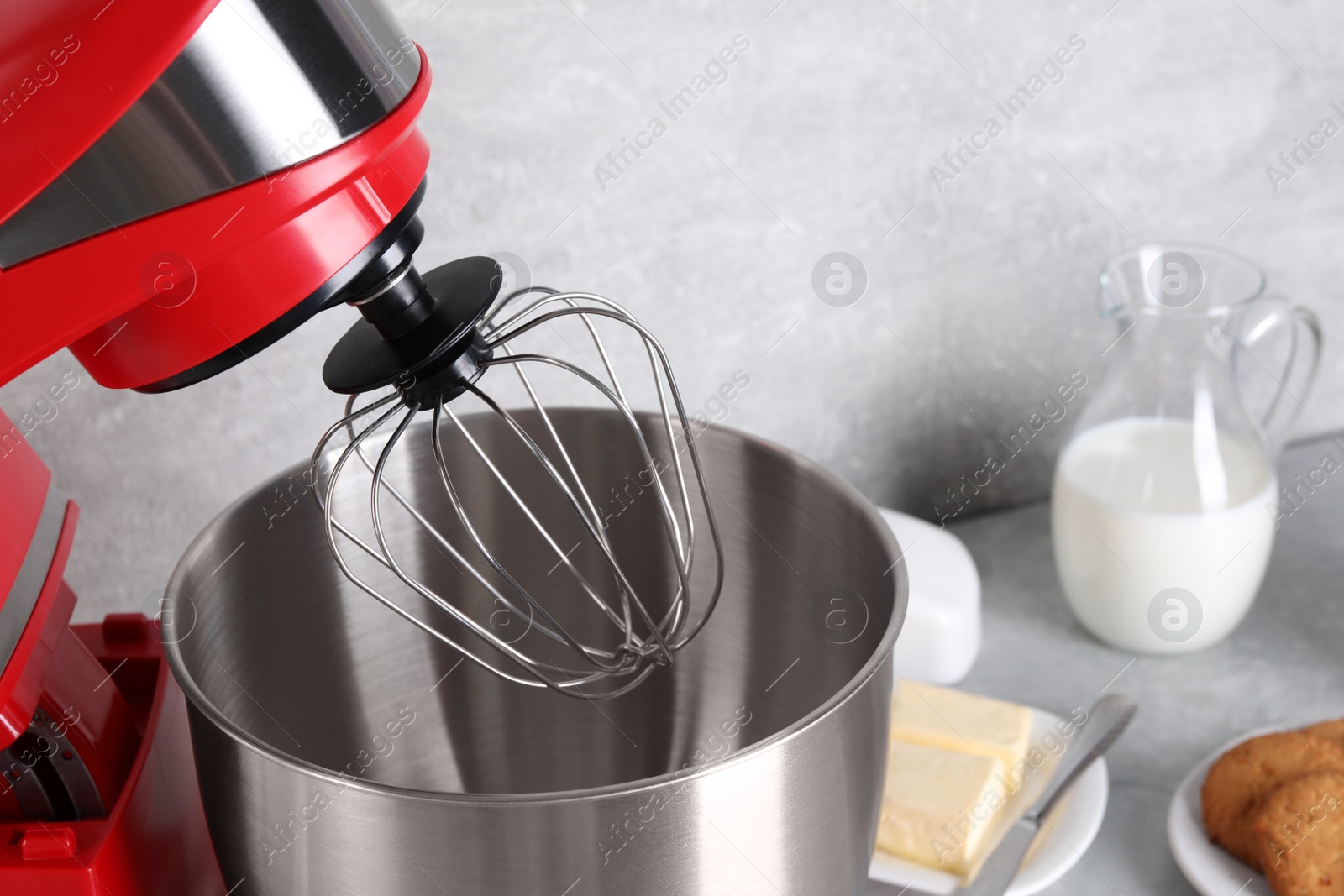 Photo of Modern red stand mixer, cookies and ingredients on light gray marble table, closeup