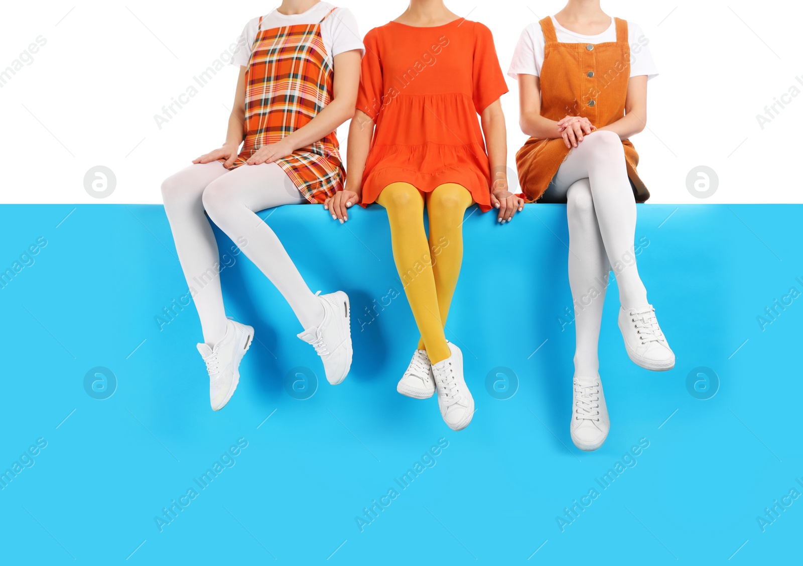 Photo of Group of women wearing colorful tights and stylish shoes sitting on color background, closeup