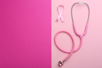 Photo of Pink ribbon as breast cancer awareness symbol and stethoscope on color background, flat lay. Space for text