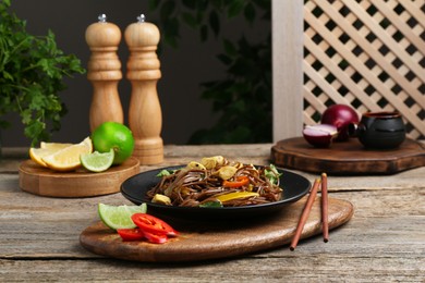 Photo of Stir-fry. Tasty noodles with meat and vegetables served on wooden table