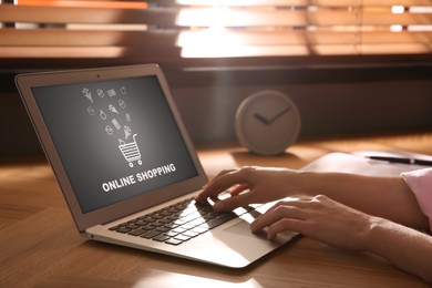 Image of Woman using laptop for online shopping at wooden table, closeup