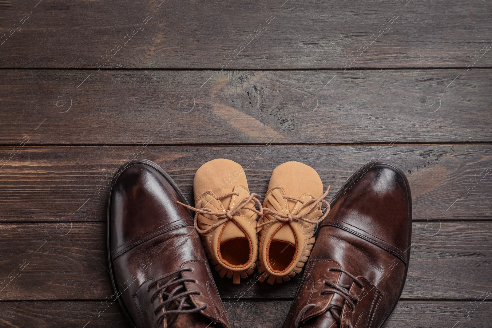 Photo of Flat lay composition with big and small shoes on wooden background. Father's day celebration