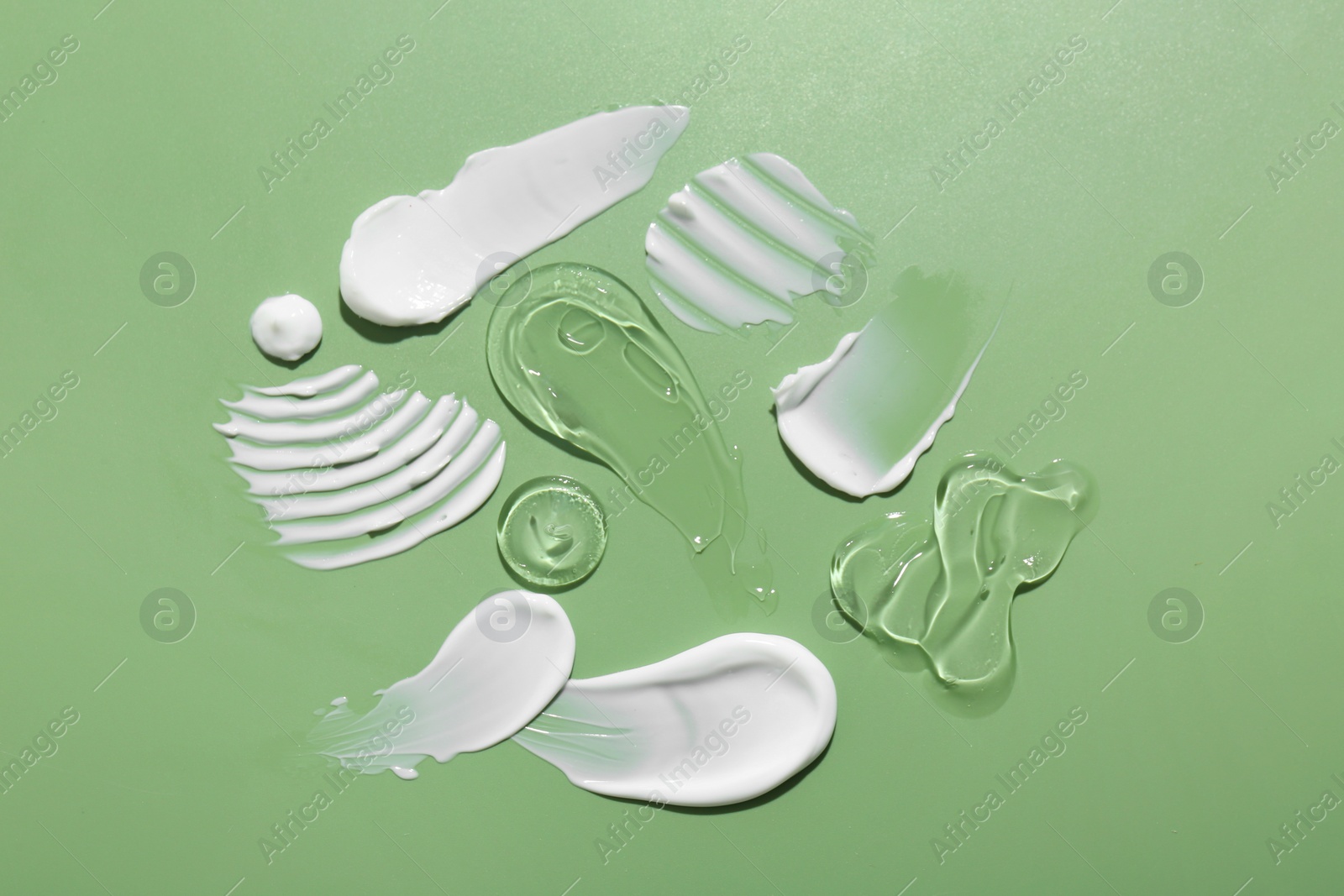 Photo of Samples of face cream on green background, top view