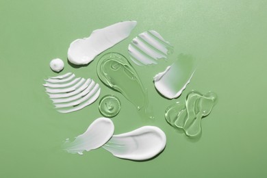 Photo of Samples of face cream on green background, top view