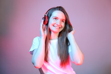 Portrait of beautiful woman with headphones in neon lights on color background