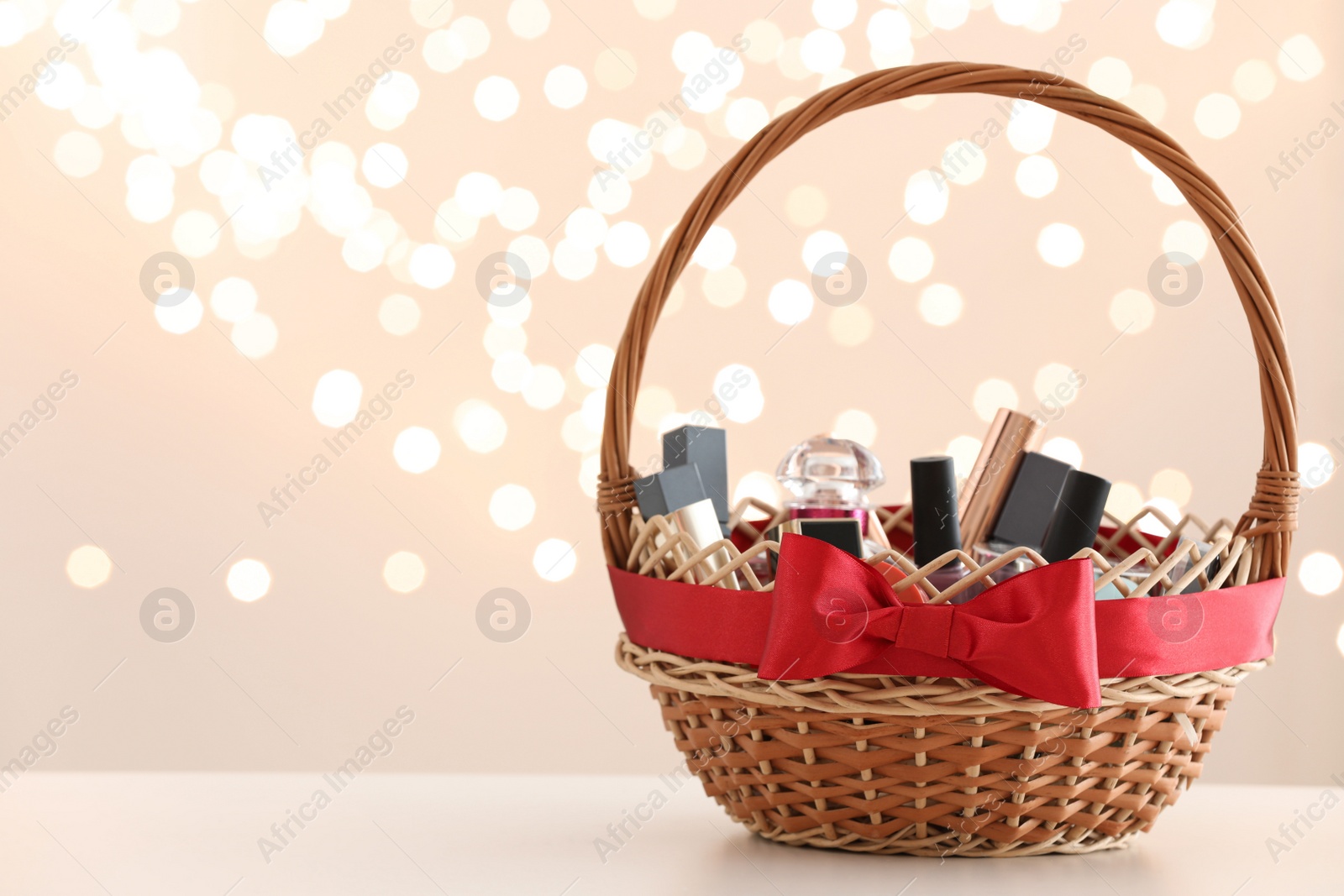 Photo of Wicker basket with cosmetics as present against blurred festive lights. Space for text