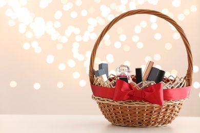 Photo of Wicker basket with cosmetics as present against blurred festive lights. Space for text
